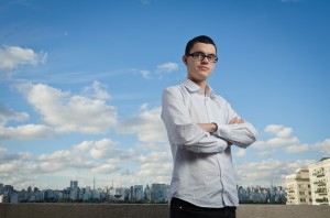 Marco Gomes, foto de divulgação 03, braços cruzados, ao fundo um céu azul com nuvens e paisagem com vista da av. Paulista