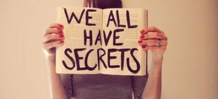 Mãos femininas segurando uma placa: Todos nós temos segredos
