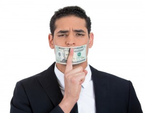 Homem fazendo sinal de "calado" com nota de 1 dólar sobre a boca