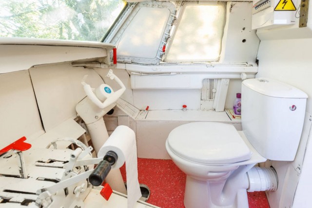 Cabine de piloto de avião com um vaso sanitário no lugar da poltrona, com manche logo à frente tudo mais original da cabine do comandante