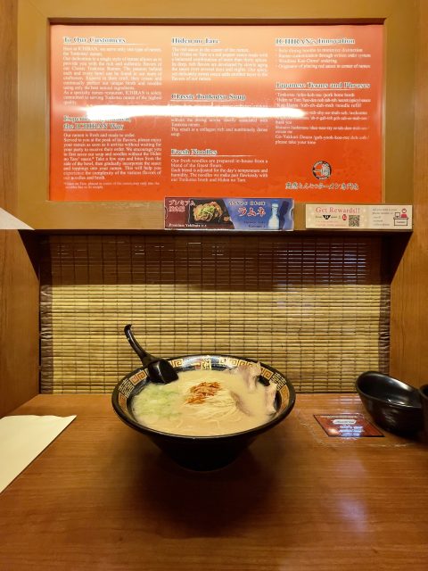 A imagem mostra uma cabine de madeira no Ichiran Ramen com uma tigela de ramen tonkotsu fumegante, servida em um ambiente privado e tranquilo.